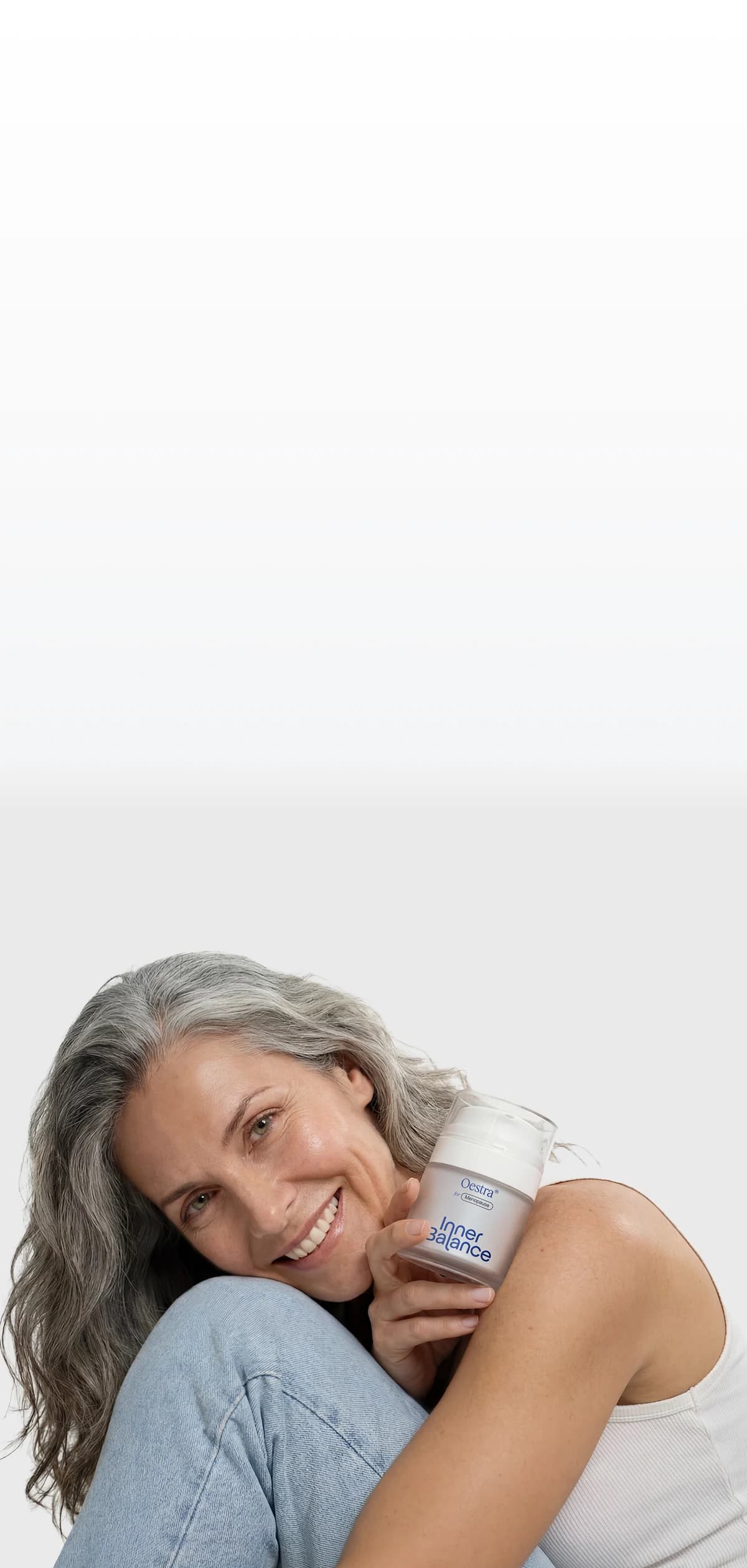 Woman smiling while holding Oestra menopause cream jar